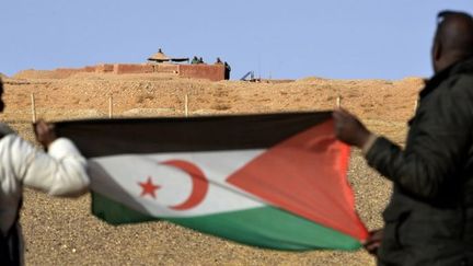 Militants du Polisario brandissant, le 3 février 2017, un drapeau de leur mouvement le long du mur séparant Sahara occidental et Maroc. (STRINGER / AFP)