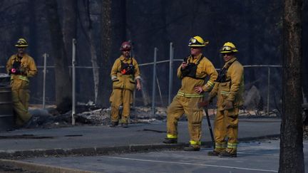 Des pompiers regardent le président américain, Donald Trump, en visite à Paradise, ville détruite par un incendie en Californie, le 17 novembre 2018. (LEAH MILLIS / REUTERS)