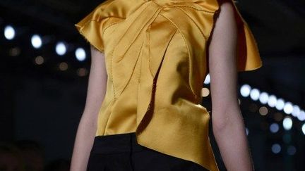 La femme de Bottega Veneta ? Un rien l'habille. Un bout d'étoffe plié, replié, superposé. Un pan de satin effiloché agencé comme un origami. Quelques points de couture invisibles et prennent forme des vêtements sculpture aux volumes calibrés avec précision. La collection se compose de manteaux et de robes d'une grande élégance sous une simplicité apparente. On devine les constructions raffinées, les jeux complexes de pliage et de pinces, les stratifications savantes. Le styliste Tomas Maier part de la laine qu'il utilise dans toutes ses variantes : drap épais, flanelles, tissus feutrés. Carrés de feuilles qu'il modèle dans des architectures inédites. Pas de boutons par exemple. Juste de fines ceintures. Pas de décorations non plus. Juste l'exploration de la matière. Au rayon des accessoires, des petits sacs et vieux bijoux de famille, comme ces médaillons portés au bout d'une chaîne. 
 (O. Morin / AFP)