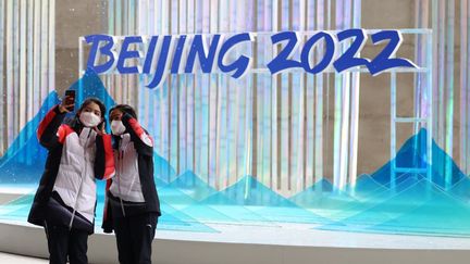 Des passantes se prennent en photo devant une installation&nbsp;pour les Jeux olympiques d'hiver, le 20 janvier 2022, à Pékin. (KOJI ITO / YOMIURI / AFP)
