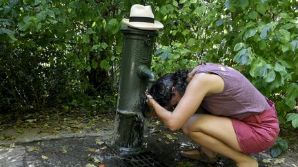 Une femme s'arrose sous une fontaine lors d'un épisode de forte chaleur, à Clamart (Hauts-de-Seine), le 10 septembre 2023. (MAGALI COHEN / HANS LUCAS / AFP)