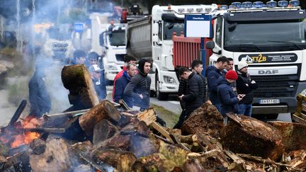 Des manifestants se tiennent près d'une barricade au dépôt pétrolier de Brest le 15 mars 2022. (FRED TANNEAU / AFP)