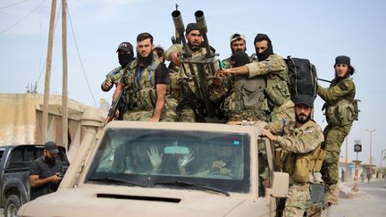 Des combattants syriens soutenus par la Turquie circulent dans la ville d'Ayn al-Arous (Syrie), le 14 octobre 2019. (BAKR ALKASEM / AFP)