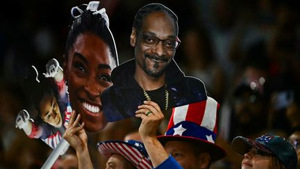 Des supporters tiennent des photos de l'Américaine Simone Biles et du rappeur américain Snoop Dogg lors de la finale de l'équipe féminine de gymnastique artistique pendant les Jeux olympiques de Paris 2024 à l'Arena Bercy, à Paris, le 30 juillet 2024. (GABRIEL BOUYS / AFP)