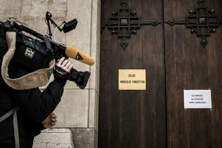 Un journaliste filme l'écriteau indiquant l'annulation des messes dans une église de Lyon, le 15 mars 2016, après le départ du prêtre de la paroisse, mis en cause dans une affaire d'agression sexuelle. (JEFF PACHOUD / AFP)