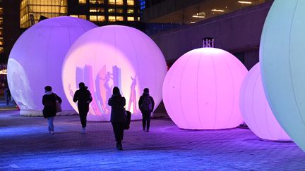 Des passants marchent à côté de lumières dans les rues de Montréal, le 14 décembre 2020. (ERIC THOMAS / AFP)