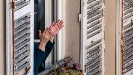 Une personne applaudit à la fenêtre d'un appartement, le 30 mars 2020, à Paris.&nbsp; (OMAR HAVANA / HANS LUCAS / AFP)