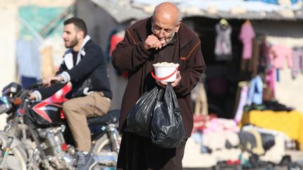 Un homme mange une ration d'aide alimentaire distribuée dans les zones rebelles d'Alep (Syrie), le 6 novembre 2016. (ABDALRHMAN ISMAIL / REUTERS)