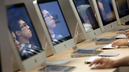 Les visages des utilisateurs de Mac se refl&egrave;tent dans les ordinateurs du g&eacute;ant Apple, le 6 octobre 2011, dans une boutique de Hong-Kong (Chine).&nbsp; (JEROME FAVRE / BLOOMBERG / GETTY IMAGES)