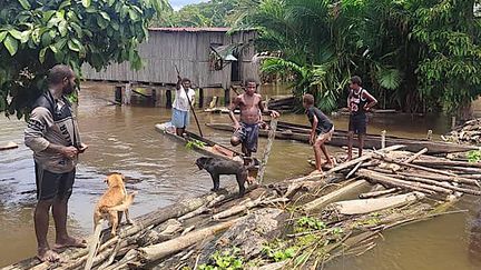 Des rescapés marchent sur un pont de fortune dans le village inondé d'Angriman, dans le district d'Angoram (Papouasie-Nouvelle-Guinée), le 25 mars 2024. (PAPUA NEW GUINEA POLICE / AFP)