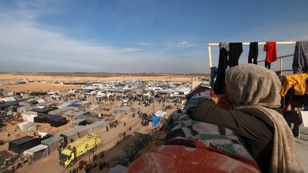 Une femme regarde depuis un toit les Palestiniens déplacés dans un camp à Rafah, près de la frontière avec l'Égypte, le 7 décembre 2023. (MOHAMMED ABED / AFP)