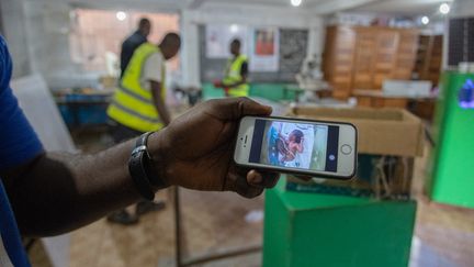 A l'hôpital African Genesis Health de Yaoundé, une jeune mère observe sur son téléphone portable chaque mouvement de son nourrisson, né prématuré et placé dans une couveuse interactive. "A la naissance, mon bébé ne faisait que 1,5 kilo. S'il n'y avait pas eu cette couveuse, il serait déjà mort", témoigne-t-elle. Dans une autre pièce, un médecin explique&nbsp;: "Cette couveuse est connectée à une caméra qui nous permet d'avoir un œil sur l'enfant depuis notre bureau. S'il y a un souci, on peut facilement interpeller un infirmier pour qu'il intervienne rapidement." (DANIEL BELOUMOU OLOMO / AFP)