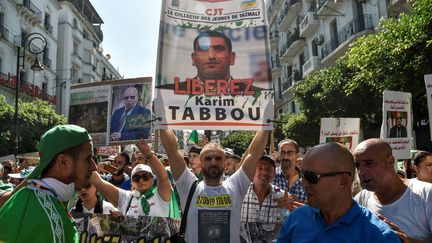 Portrait de Karim Tabbou brandi par les manifestants lors d'un rassemblement dans les rues d'Alger, le 27 septembre 2019, au lendemain de son arrestation. Karim Tabbou est devenu l'un des principaux visages du Hirak, le mouvement de contestation algérien.&nbsp; ((RYAD KRAMDI / AFP))