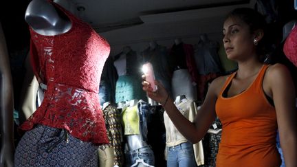 Une cliente dans une boutique de vêtements, pendant une coupure de courant, à San Cristobal, au Venezuela, le 25 avril 2016.&nbsp; (CARLOS EDUARDO RAMIREZ / REUTERS)