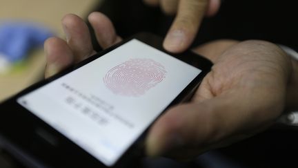 Un journaliste teste le lecteur d'empreinte digitale de l'iPhone 5S, &agrave; P&eacute;kin (Chine), le 11 septembre 2013. (JASON LEE / REUTERS)