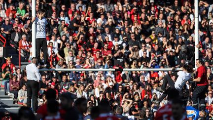 Deux militants du mouvement écologiste Dernière rénovation escaladent les poteaux de l'en-but du Stade Toulousain lors du match contre le Stade Français à Toulouse, samedi 5 novembre 2022. (CHARLY TRIBALLEAU / AFP)