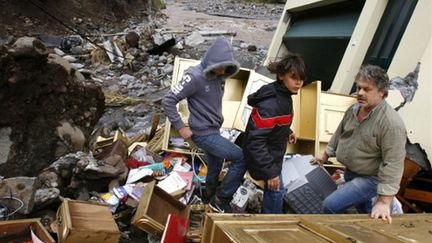 Une famille contemple les dégâts de sa maison à Funchal, capitale de l'île portugaise de Madère (AFP PHOTO - GREGORIO CUNHA)