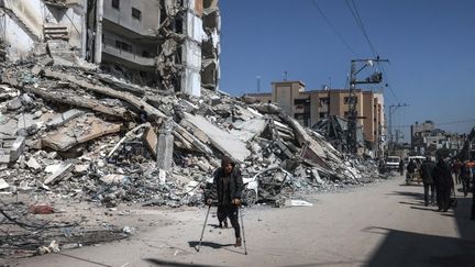 Un habitant passe devant un immeuble détruit de Rafah, après un bombardement israélien, le 12 mars 2024. (MOHAMMED ABED / AFP)