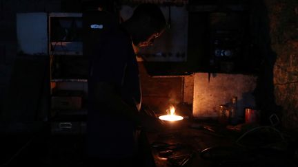 Un homme travaille dans la pénombre à Caracas, le 8 mars. (IVAN ALVARADO / REUTERS)