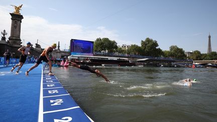 Des athlètes plongent dans la Seine, pour l'épreuve de triathlon masculin individuel, lors de Jeux olympiques de Paris, le 31 juillet 2024. (ANNE-CHRISTINE POUJOULAT / AFP)