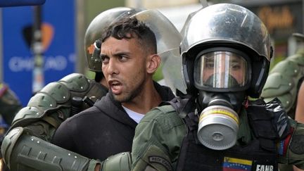 Des membres de la garde nationale bolivarienne arrêtent des opposants au président vénézuélien, qui participaient à une manifestation, à Caracas (Venezuela), le 30 juillet 2024. (YURI CORTEZ / AFP)