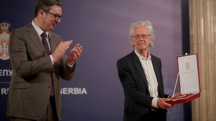 Peter Handke applaudi par le président serbe Aleksandar Vucic lors de la cérémonie de remise de&nbsp;l'une des plus grandes décorations de la Serbie, le 9 mai 2021 (OLIVER BUNIC / AFP)