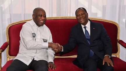 Le président ivoirien Alassane Ouattara (à droite) serre la main de son prédécesseur et ancien rival Laurent Gbagbo (à gauche), au palais présidentiel à Abidjan, le 27 juillet 2021. (ISSOUF SANOGO / AFP)