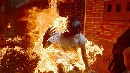 Un manifestant prend feu lors d'affrontements avec la police anti-émeute lors d'une manifestation contre le président vénézuélien Nicolas Maduro, à Caracas, le 3 mai 2017. (RONALDO SCHEMIDT / AFP)