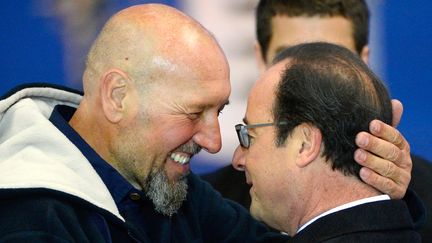 L'ex-otage Serge Lazarevic &eacute;treint Fran&ccedil;ois Hollande sur le tarmac de Villacoublay, pr&egrave;s de Paris, le 10 d&eacute;cembre 2014, lors de son retour en France. (BERTRAND GUAY / AFP)