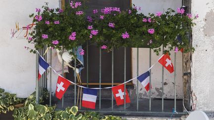 Des drapeaux français et suisse accrochés à un balcon de&nbsp;Saint-Gingolph, un village transfrontalier situé au bord du Lac Léman, en Haute-Savoie. (VINCENT ISORE / MAXPPP)