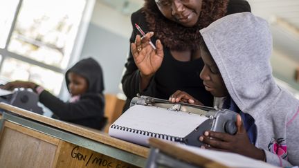 Une enseignante aide son élève à utiliser une machine à écrire le braille, le 14 juin 2016 à Ongwediva (Namibie). (OLEKSANDR RUPETA / NURPHOTO / AFP)