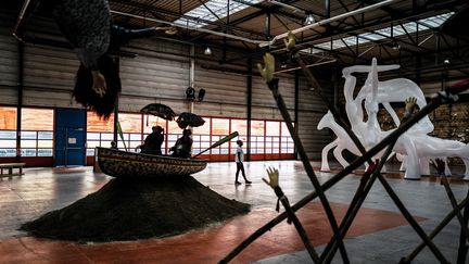 Un visiteur&nbsp;passe derrière l'installation de l'artiste sud-africain&nbsp;Simphiwe Ndzube à la Biennale d'art contemporain de Lyon, le 16 septembre 2019 dans une ancienne usine Fagor-Brandt, à l'avant-veille de l'ouverture au public de la manifestation. (JEFF PACHOUD / AFP)