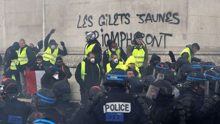 Des "gilets jaunes" face à des policiers, au pied de l'arc de triomphe, à Paris, le 1er décembre 2018. (GEOFFROY VAN DER HASSELT / AFP)