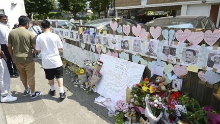 Des Londoniens ont déposé des fleurs devant des portraits de personnes disparues dans l'incendie de la tour Grenfell, dans le quartier de North Kensington, dimanche 18 juin 2017.&nbsp; (JOHN STILLWELL / SIPA / AP)