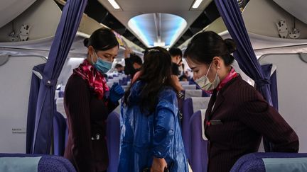 Des hôtesses de l'air portant des masques pour se protéger du coronavirus. (HECTOR RETAMAL / AFP)