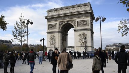 Des touristes au pied de l'Arc de Triomphe, à Paris, le 13 novembre 2015. (FRANCK FIFE / AFP)