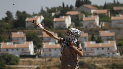 Un manifestant palestinien lance des pierres contre les soldats isra&eacute;liens, &agrave; proximit&eacute; de la colonie de Nabi Saleh, en Cisjordanie, le 6 juillet 2012. (MOHAMAD TOROKMAN / REUTERS)