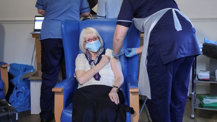 Une femme de 88 ans reçoit une dose de vaccin contre le Covid-19, à Hamilton (Ecosse), le 14 décembre 2020. (RUSSELL CHEYNE / POOL)