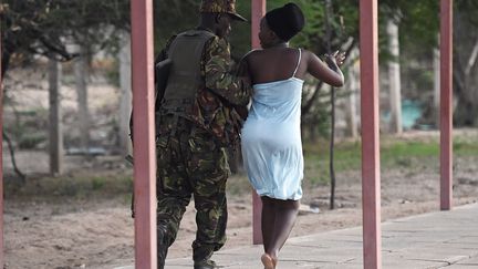 Un membre des forces de s&eacute;curit&eacute; escorte une &eacute;tudiante, sur le campus de Garissa (Kenya), apr&egrave;s l'attaque des shebabs islamistes, jeudi 2 avril 2015. (CARL DE SOUZA / AFP)