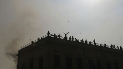 Des partisans du r&eacute;gime jettent des pierres sur des opposants depuis le toit du minist&egrave;re des Transports et des Communications dans le centre du Caire (Egypte), le 17 d&eacute;cembre 2011. (MOHAMMED ABED / AFP)