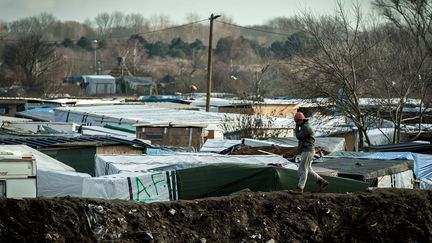 Un migrant marche sur un remblai de terre qui entoure la "jungle", le 19 Février 2016 à Calais (Pas-de-Calais) (PHILIPPE HUGUEN / AFP)