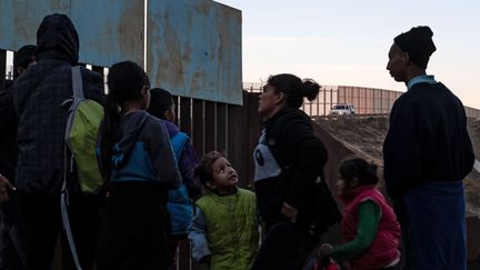 Des migrants originaires d'Amérique centrale font face à la barrière qui sépare le Mexique des Etats-Unis, au niveau de Playas de Tijuana (Mexique), le 12 décembre 2018. (GUILLERMO ARIAS / AFP)