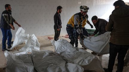 Des habitants et un sauveteur des Casques blancs syriens entassent les corps de civils tués lors d'un bombardement du régime syrien dans le village de Qoqfin, dans la province d'Idlib, le 25 novembre 2023. (MOHAMMED AL-RIFAI / AFP)