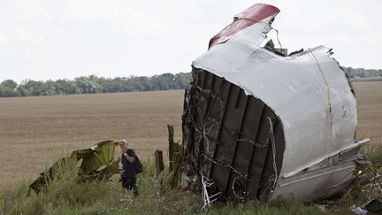 Un enqu&ecirc;teur examine les d&eacute;bris de l'avion de la compagnie Malaysia Airlines, pr&egrave;s du village de Hrabove, dans l'est de l'Ukraine, mardi 22 juillet 2014.&nbsp; (VADIM GHIRDA / AP / SIPA)