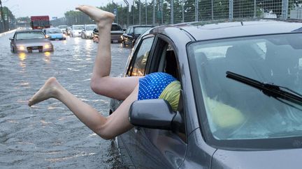 Une jeune femme retourne dans son v&eacute;hicule cern&eacute; par les eaux &agrave; Toronto (Canada), le 8 juillet 2013. (FRANK GUNN / AP / SIPA)