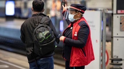 Un agent SNCF renseigne un passager sur le quai de la gare Montparnasse, le 12 mai 2020 à Paris. (THOMAS SAMSON / AFP)