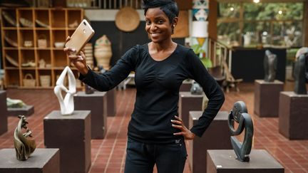 Conservatrice adjointe à la Galerie d'art nationale du Zimbabwe, Valerie Tafadzwa Sithole pose avec son smartphone à Harare le 9 novembre 2018. Elle communique avec des galeries internationales et partage des portefeuilles d'artistes sur des plateformes de médias sociaux, pour plus de visibilité. (JEKESAI NJIKIZANA / AFP)