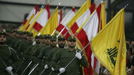 Des combattants du Hezbollah portent le drapeau libanais et le drapeau jaune du mouvement chiite &agrave; l'occasion du Jour des martyrs, &agrave; Beyrouth (Liban), le 11 novembre 2009. (RAMZI HAIDAR / AFP)