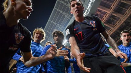 Mario Mandzukic (au centre) offre son aide au photographe de l'AFP Yuri Cortez, après que celui-ci a été renversé par les joueurs de la Croatie lors de la célébration de leur deuxième but face à l'Angleterre (2-1), le 11 juillet. (YURI CORTEZ / AFP)