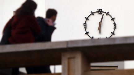 Des passants jettent un coup d'oeil à l'horloge de la mairie de Biarritz, quelques minutes après le couvre-feu, le 16 janvier 2021. (GAIZKA IROZ / AFP)